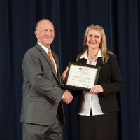 Doctor Potteiger posing for a photo with an award recipient in a black blazer and white button down